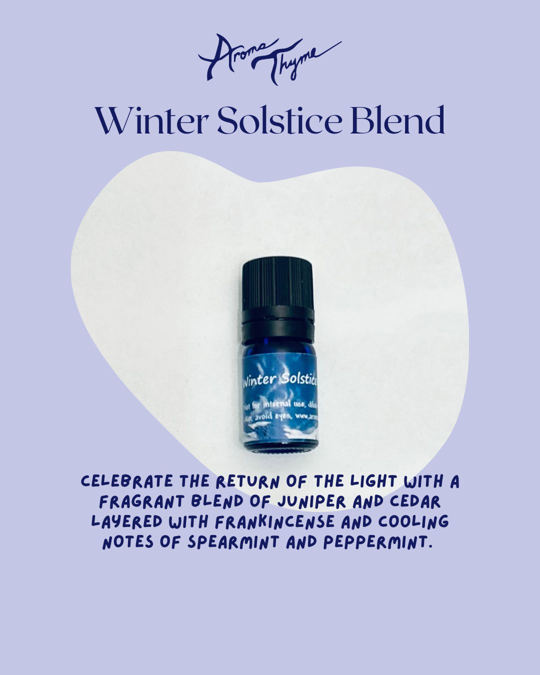 Aroma Thyme Winter Solstice Blend essential oil bottle on a heart-shaped white pillow with descriptive text on a light purple background.