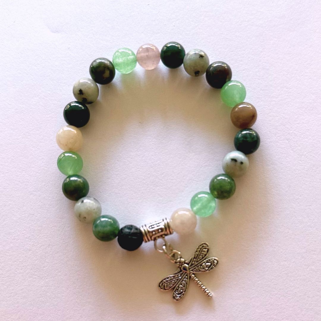 gemstone bracelet with a dragonfly charm on a light pink background