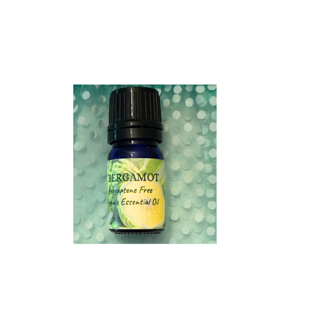 A small essential oil bottle labeled 'BERGAMOT' with a black cap, set against a textured light green background with a subtle bokeh effect.