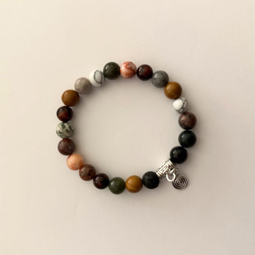 Multicolored beaded bracelet with a silver charm on a beige background