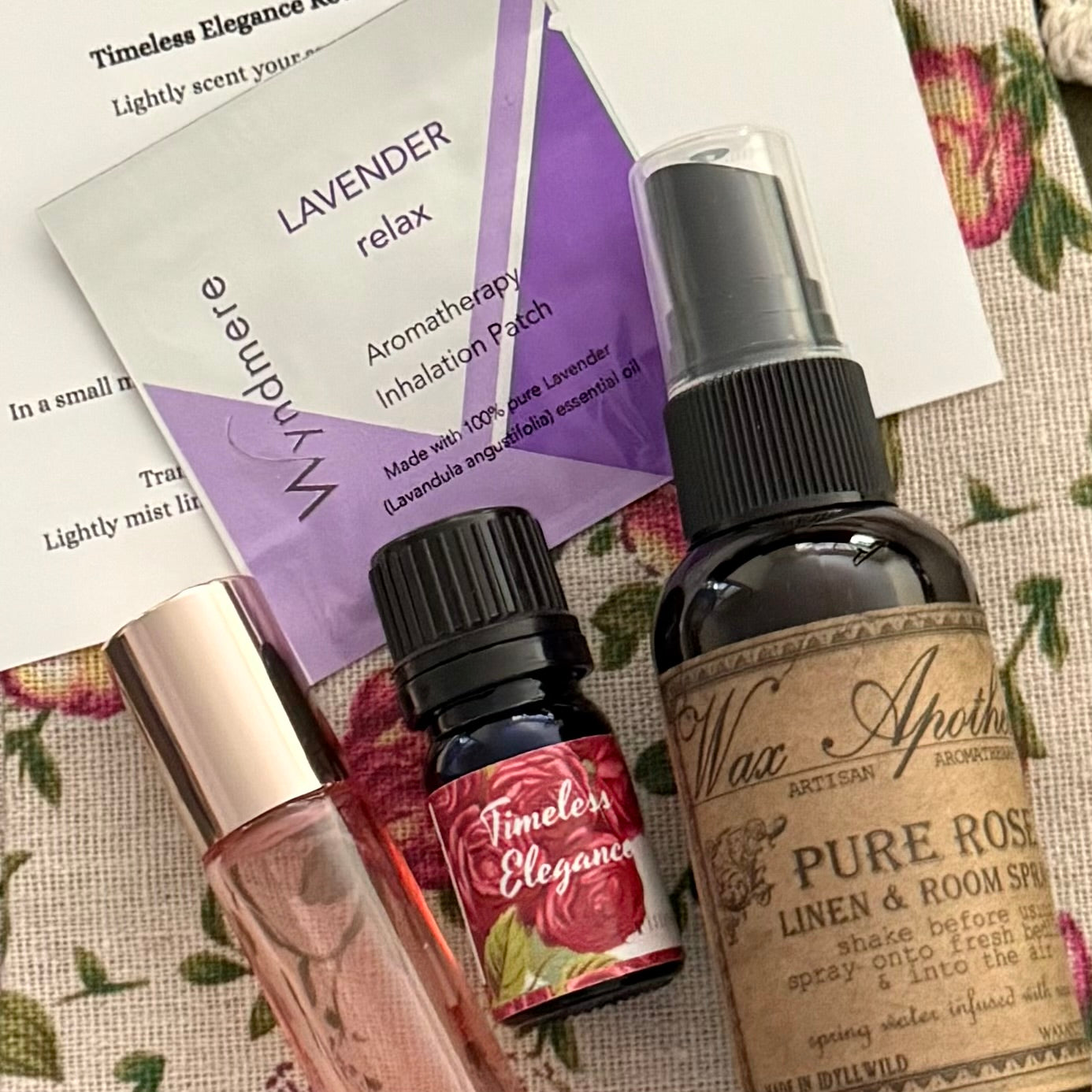 Collection of aromatherapy products including a spray bottle, rollerball, and essential oil bottle on a floral fabric background.